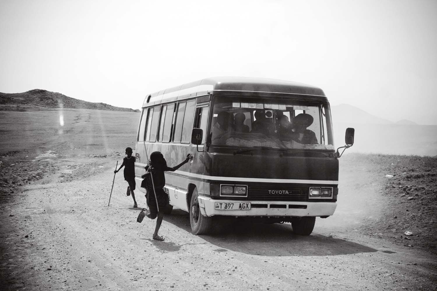 ￼Young Maasai beg for food or change from a bus full of pilgrims on their way to see Reverend Ambilikile Mwasapila, a faith healer in Tanzania’s remote district of Loliondo.