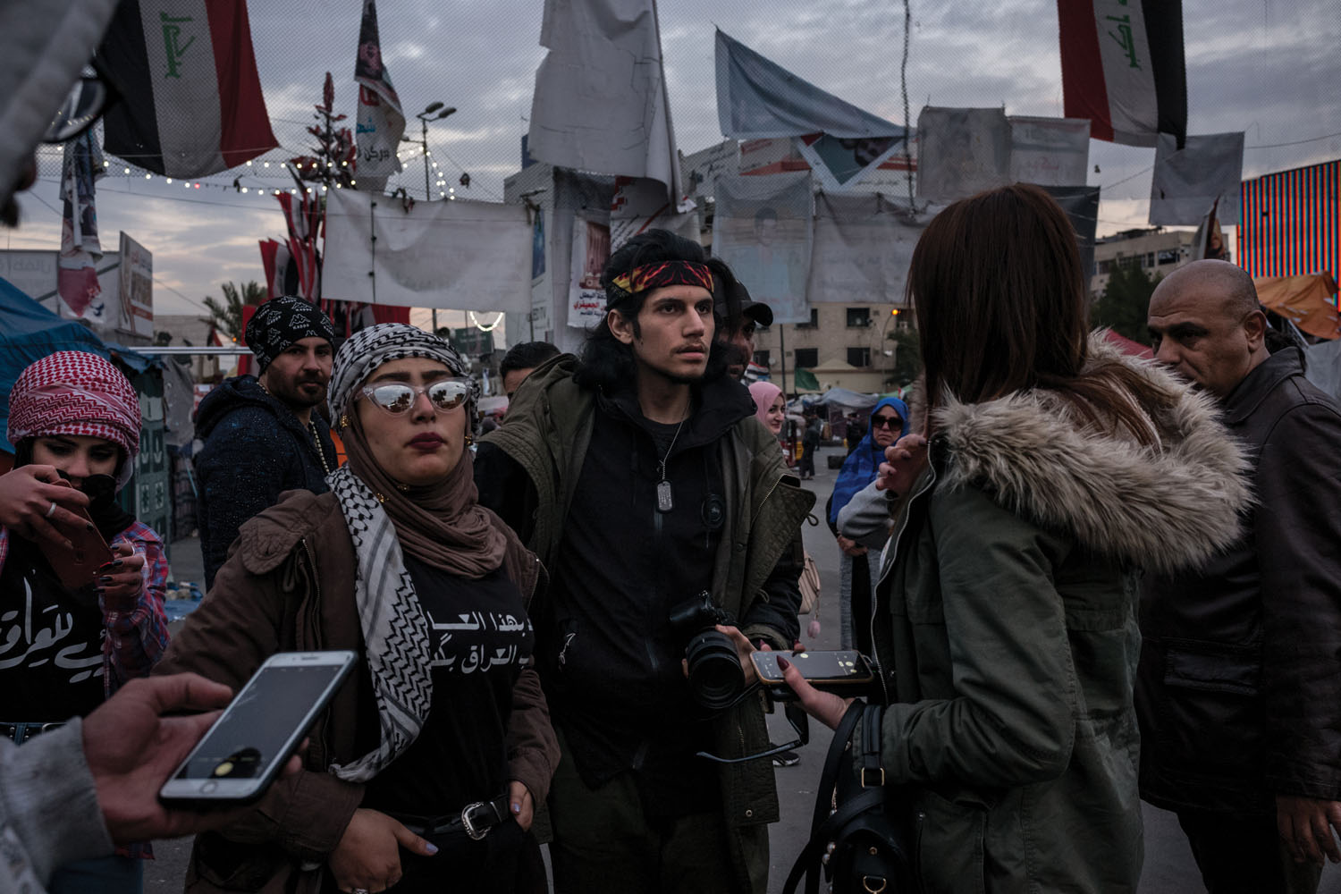 Filmmaker Mohamed Khalili (center), 22, and protester Asraa al Tai (left) scout locations for a short film documenting women's support for the Tishreen Revolution.